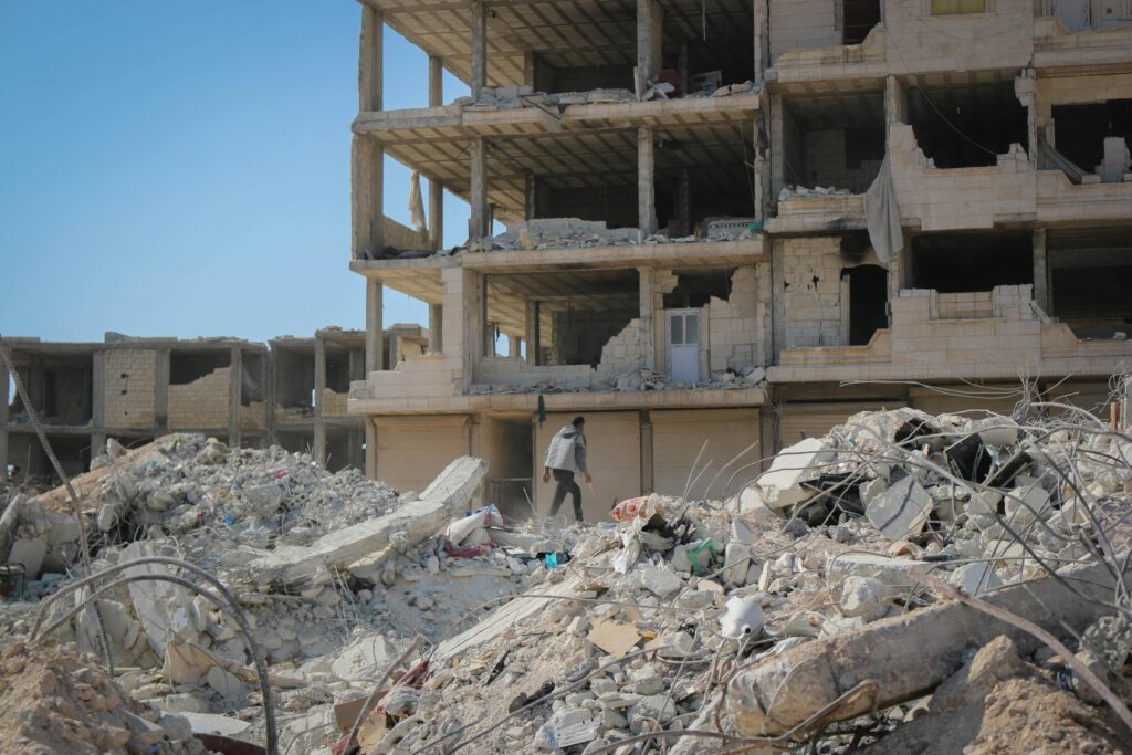 A man walks through rubble in Idlib, Syria, illustrating destruction from conflict.